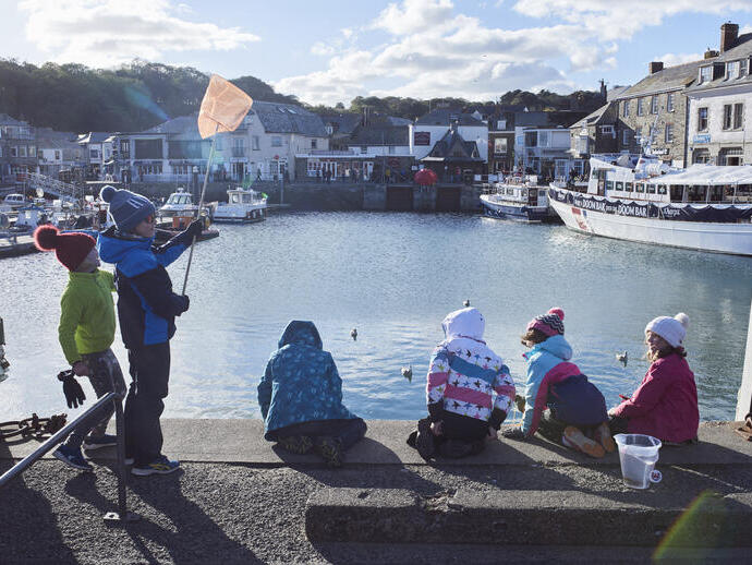Children sat on a harbour wall fishing for crabs