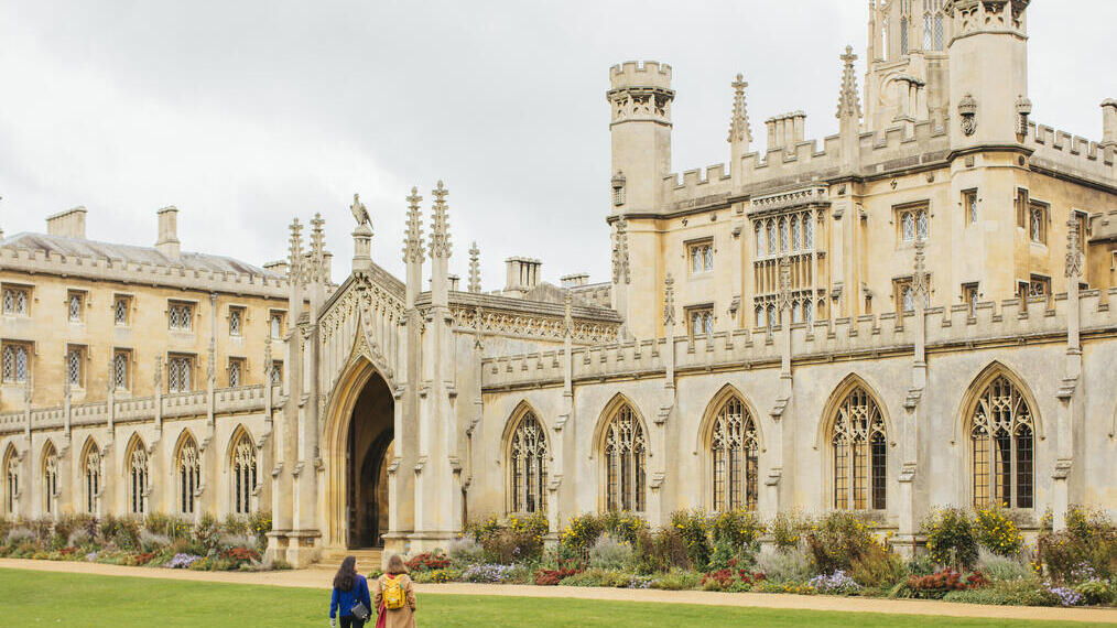 Two women walking across the grass in front of an historic building