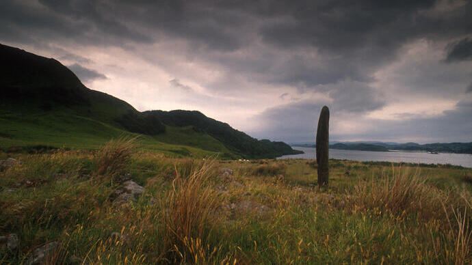A singular standing stone on the shores of a lake.