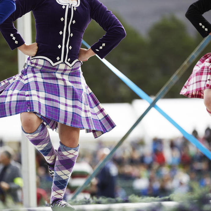 Tre ragazze in kilt che ballano danze scozzesi sul palco