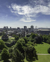 Vista aérea del parque Bute, en Cardiff, con árboles verdes en primer plano y cielos azules