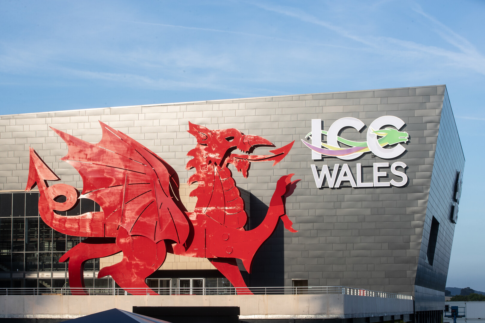 Convention Centre exterior in daylight, featuring a red Welsh dragon and a sign reading: ICC Wales.