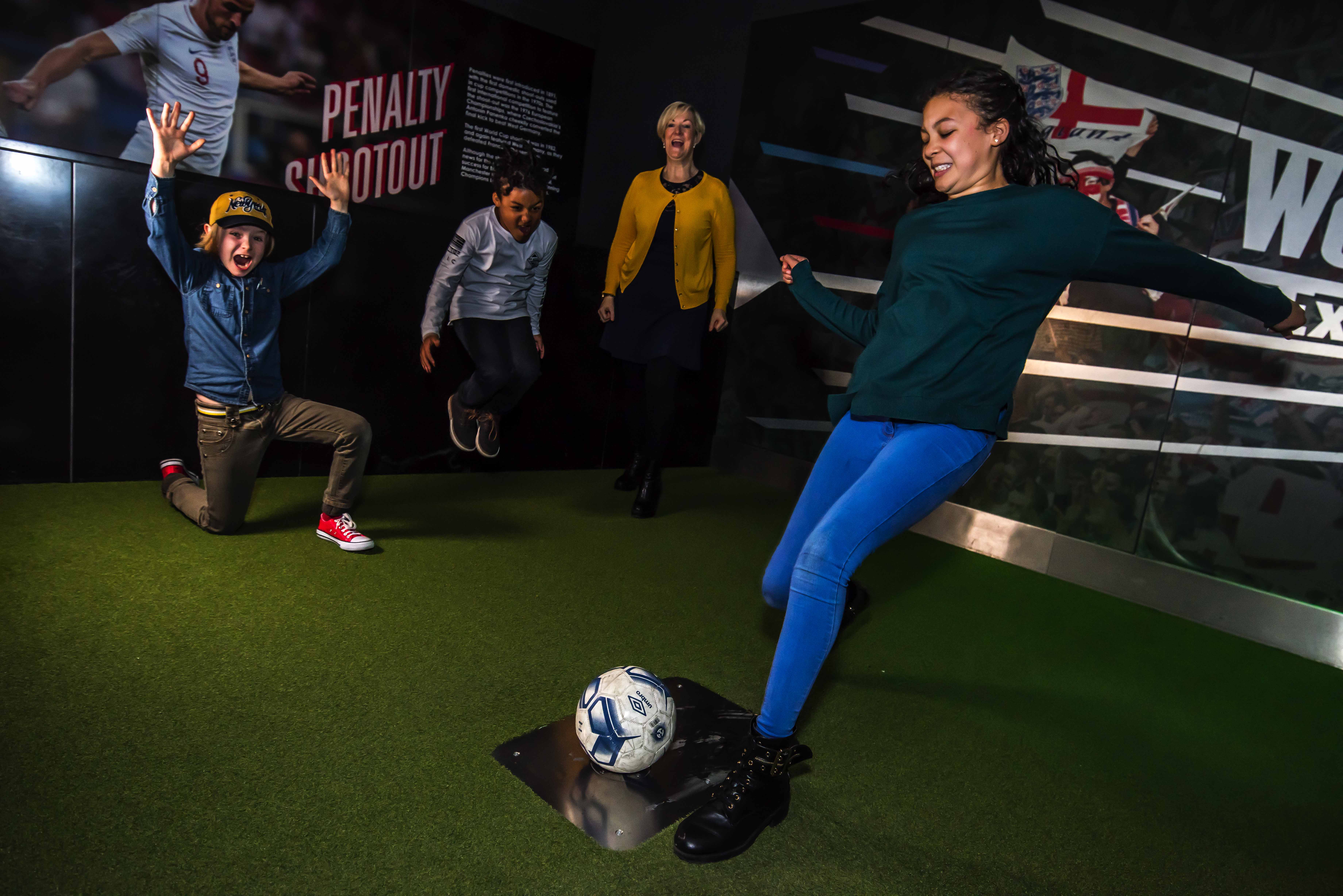 A group of people taking part in a penalty shootout exhibit in the National Football Museum in Manchester