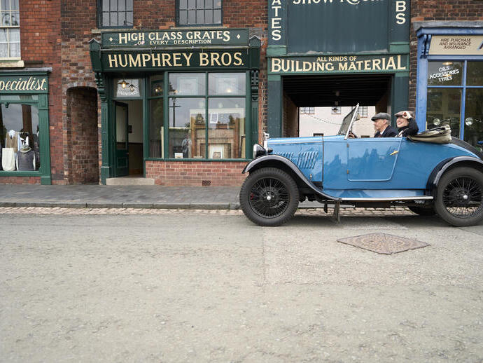 Two people inside a vintage car at a living museum