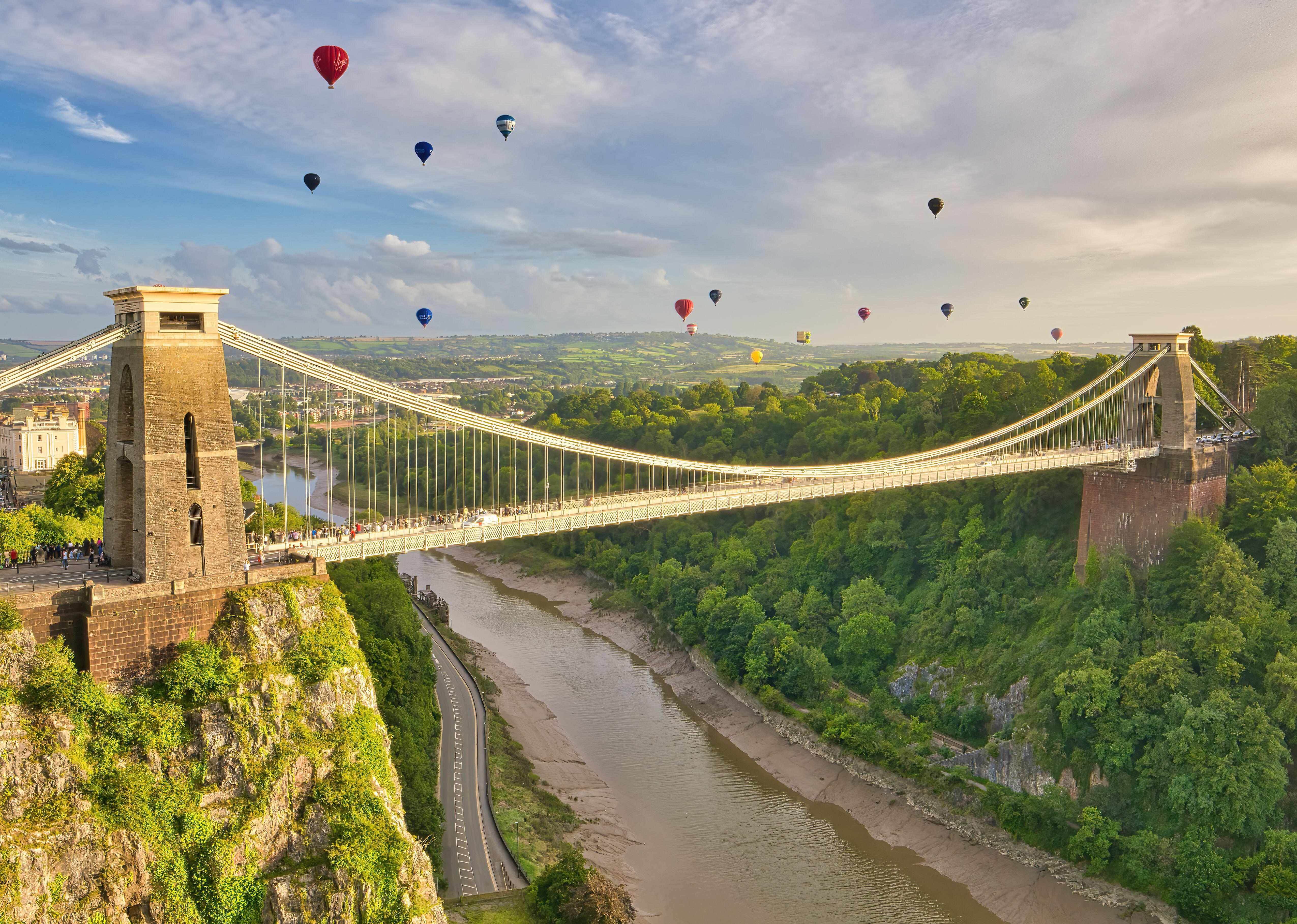 Aerial view of a large suspension bridge with hot air balloons taking to the air