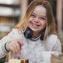Young female with Down's Syndrome sat at a table laughing
