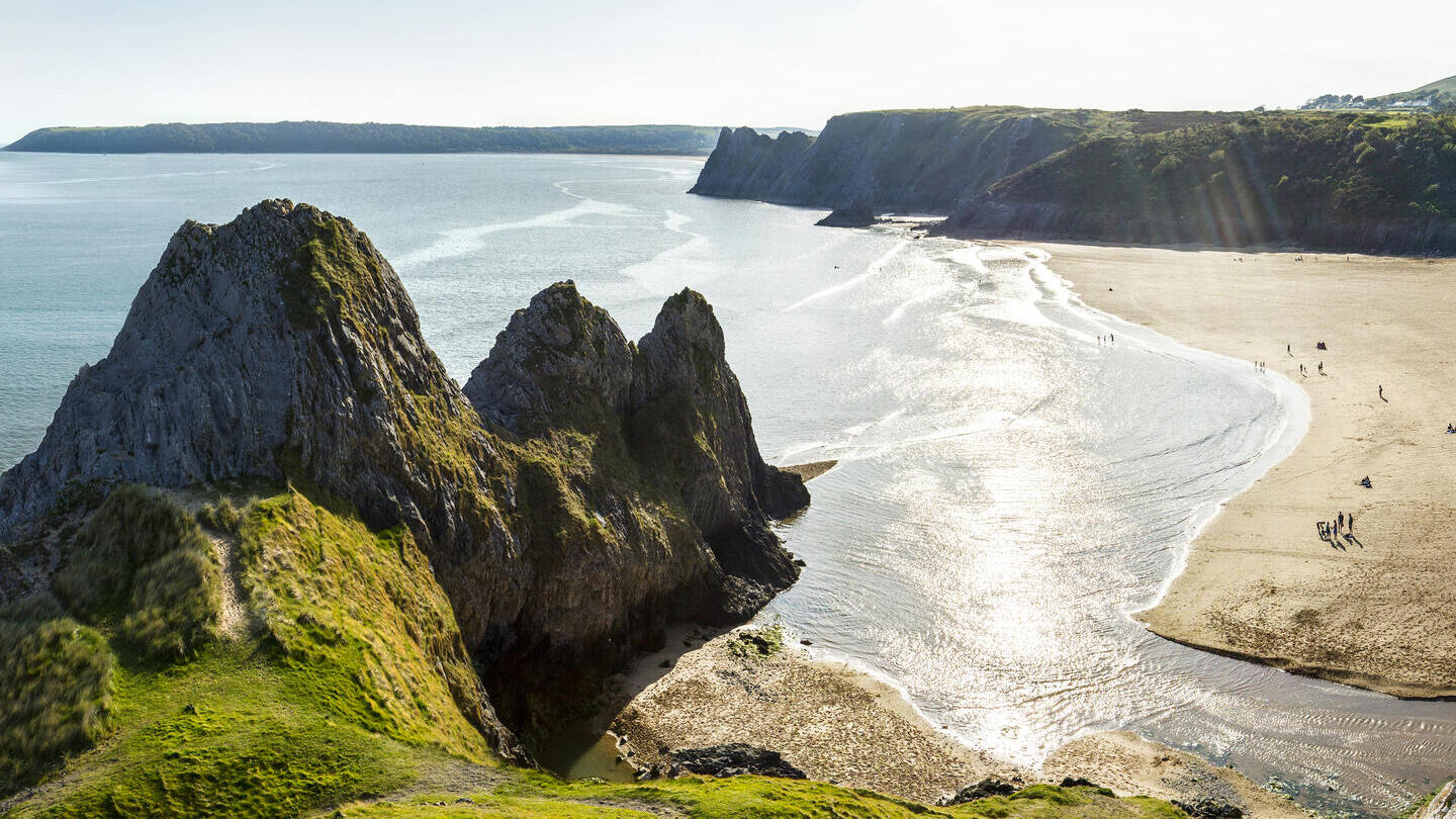 Coastline with a sandy beach and rocky peninsula.
