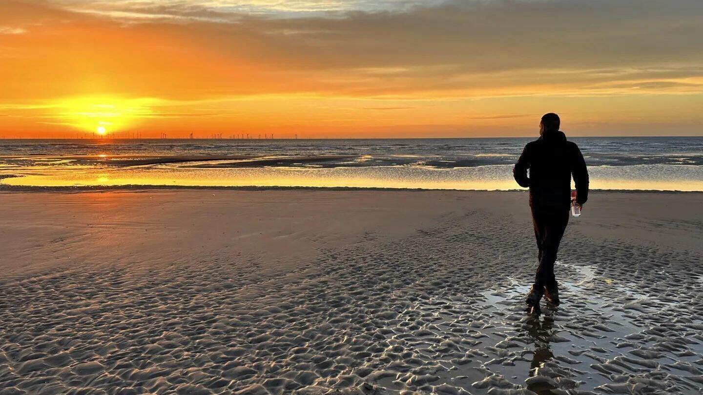 Autumn-island escape. Man walking on a beach