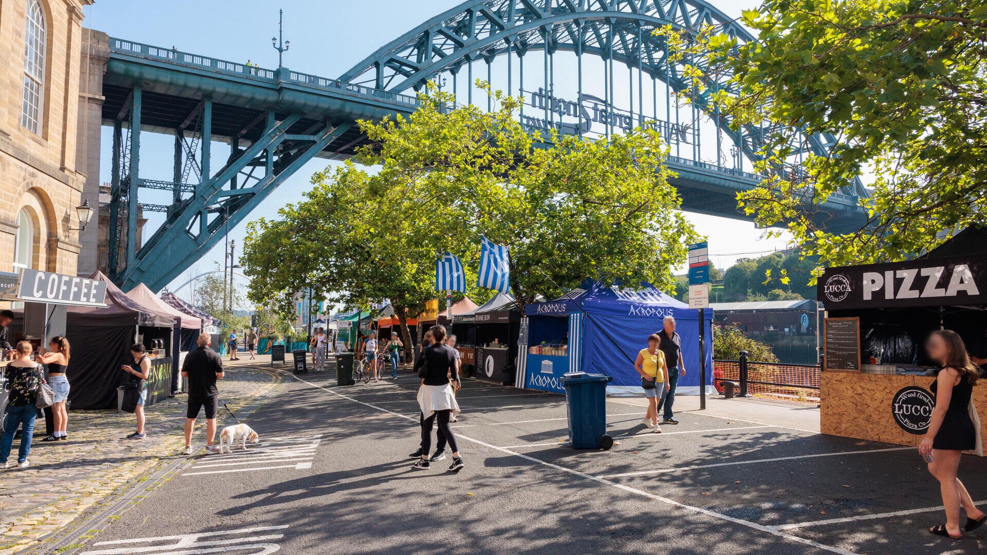 Menschen, die an Marktständen in der Nähe einer Brücke vorbeigehen