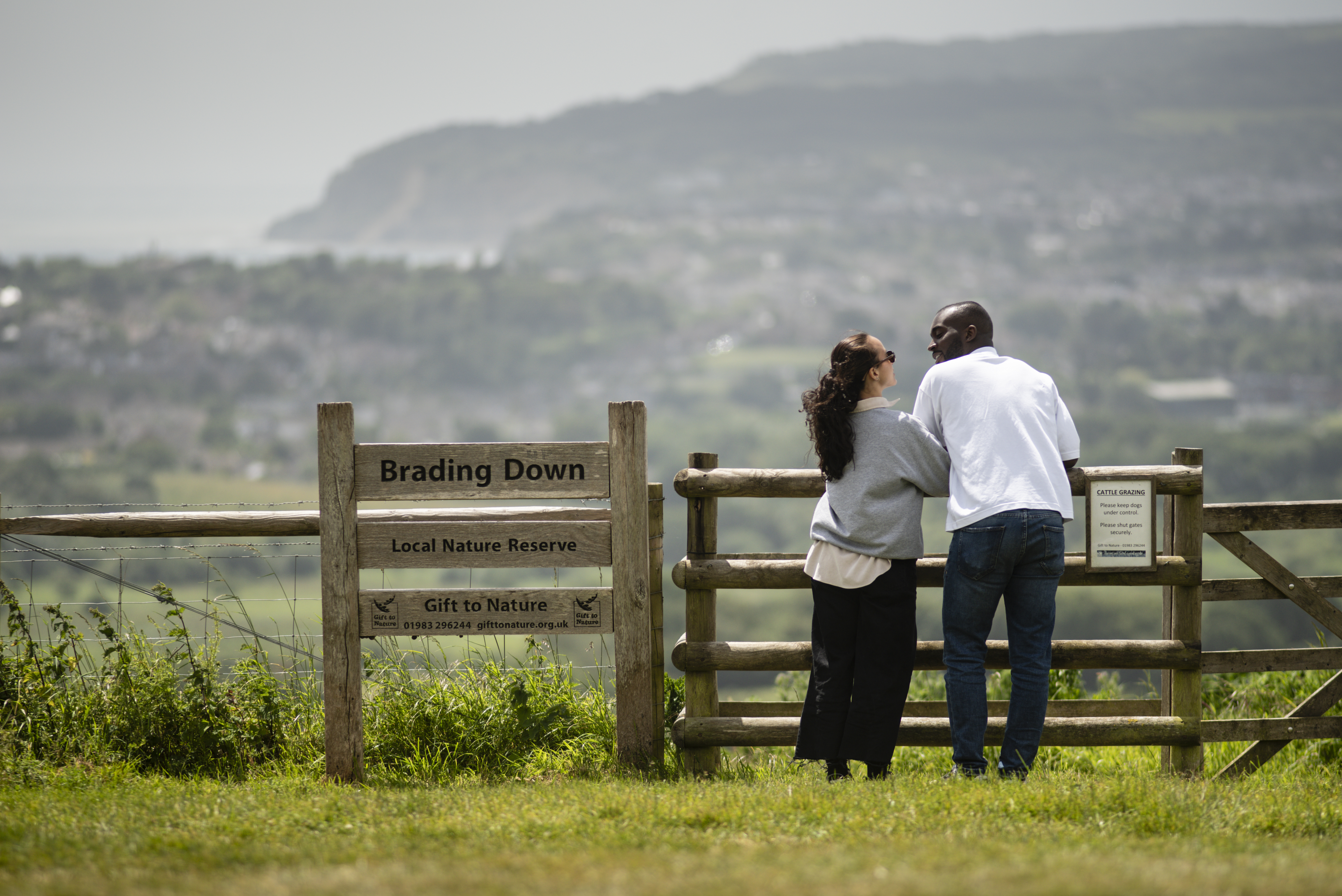 A man and a woman stand at gate with the town and sea beyond