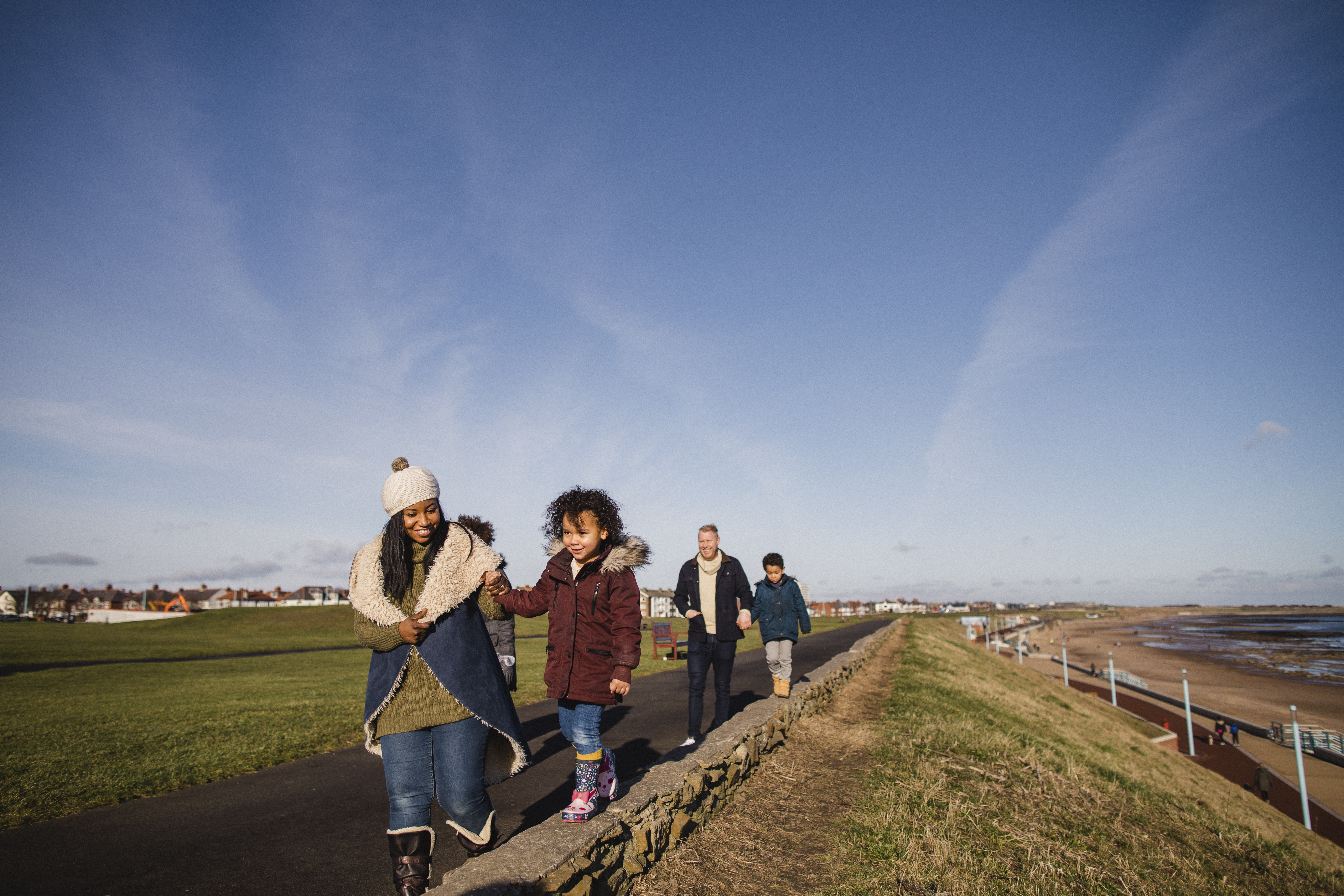 Famille marchant sur un sentier le long de la côte par une journée ensoleillée avec ciel bleu