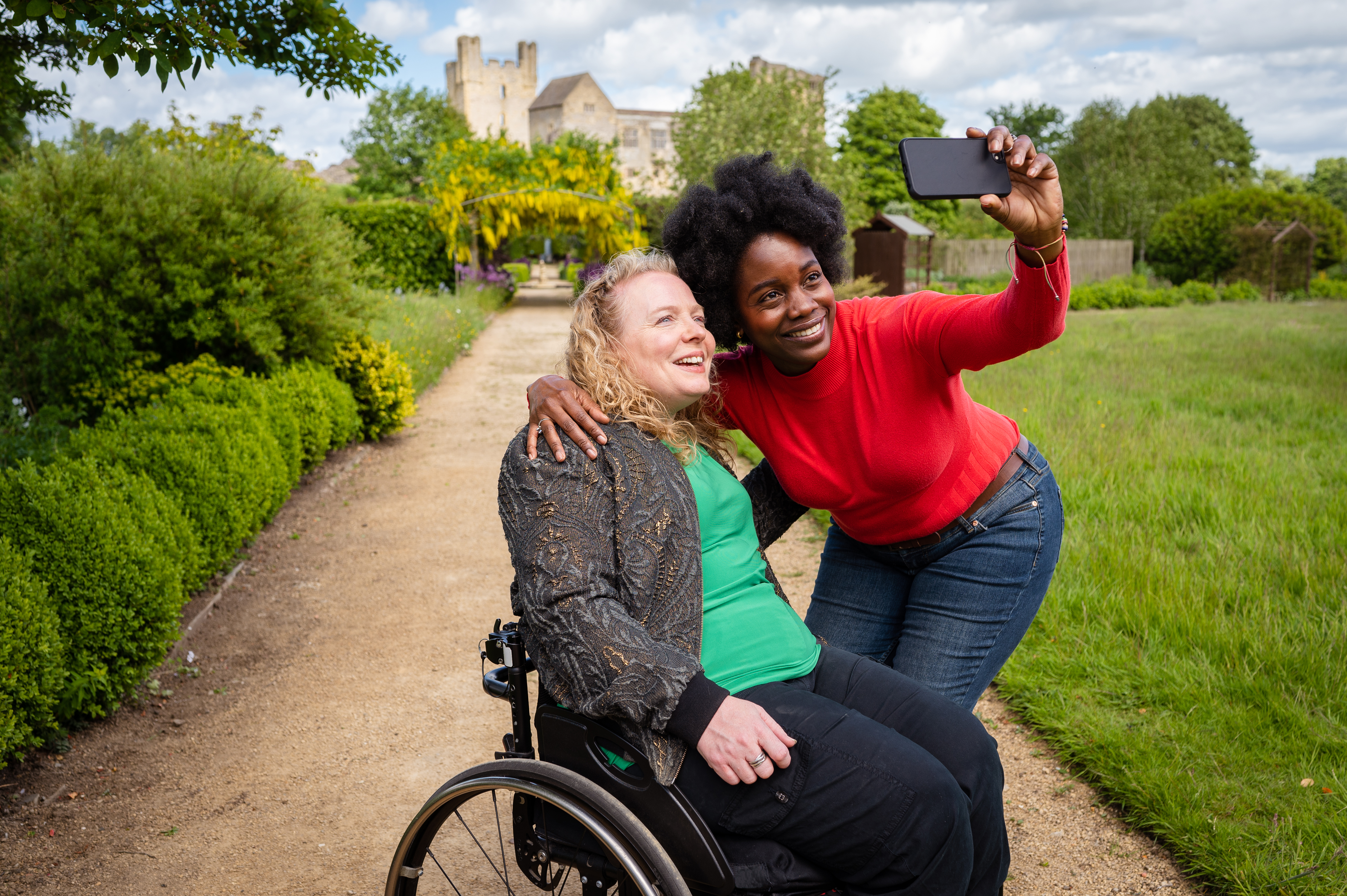Two women walking through the garden, with a castle in the background