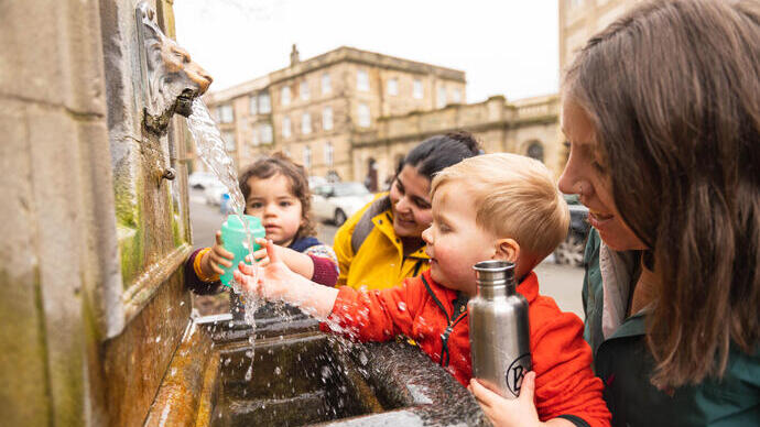 Two women and two small children getting water from a fountain