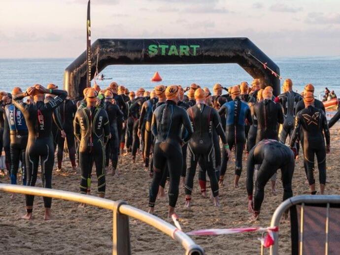 Competitors standing at the start line of a race wearing wetsuits.