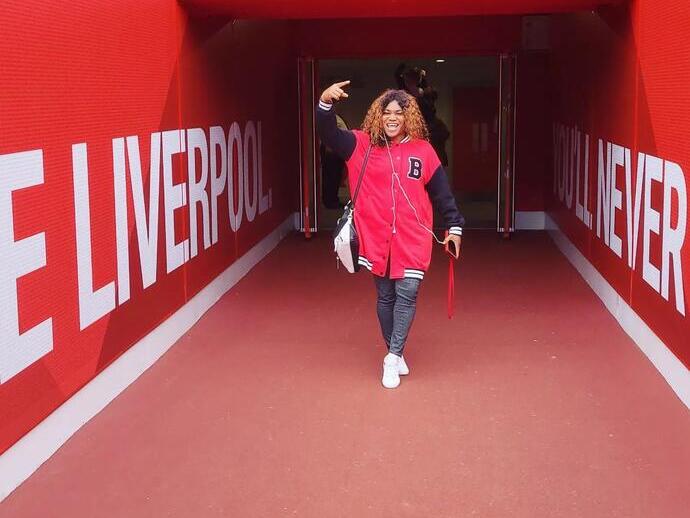 A woman posing while on a stadium tour of Anfield, Liverpool.