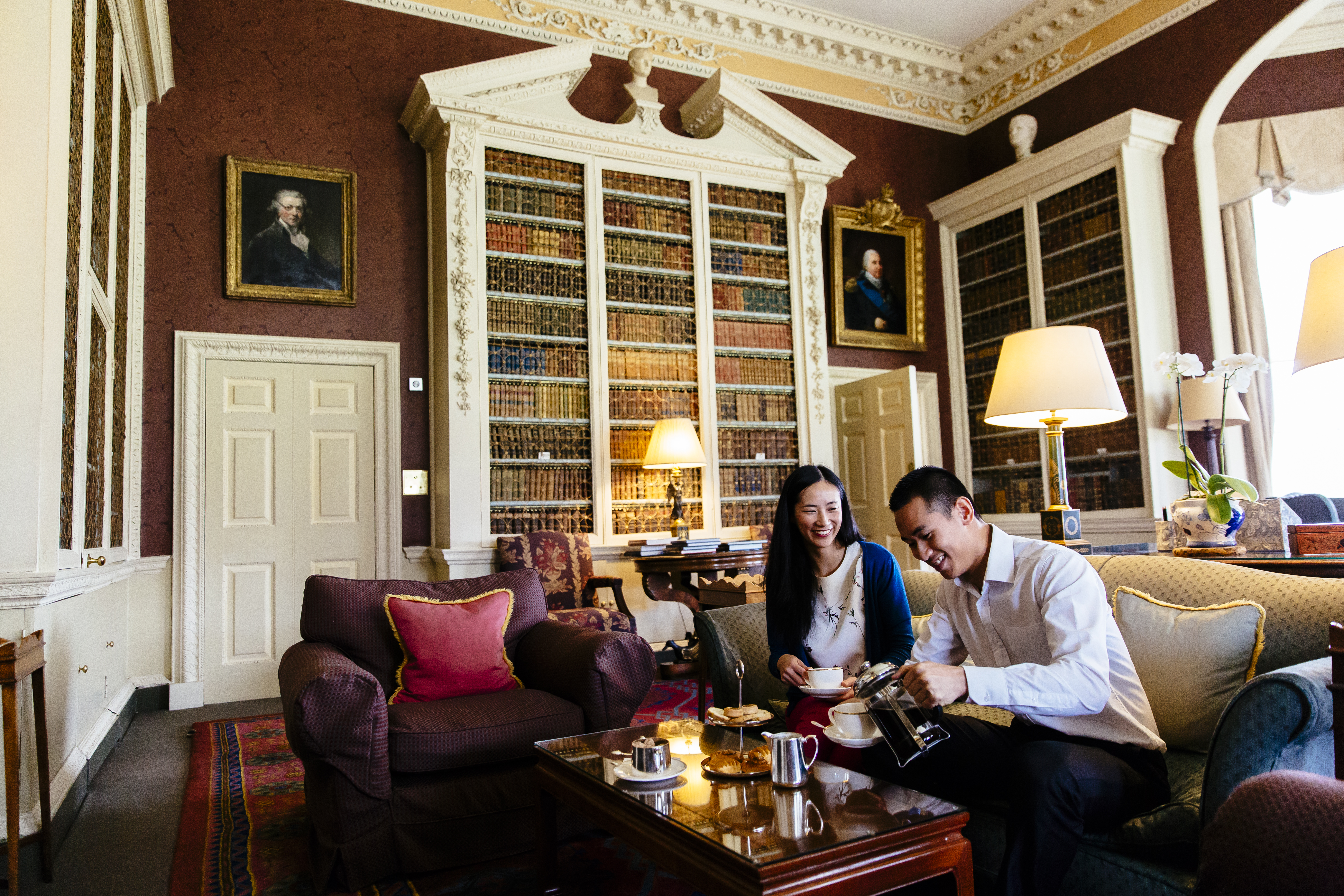 An asian couple, sitting on a sofa, having afternoon tea