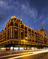Harrods department store lit up at night. Dark skies