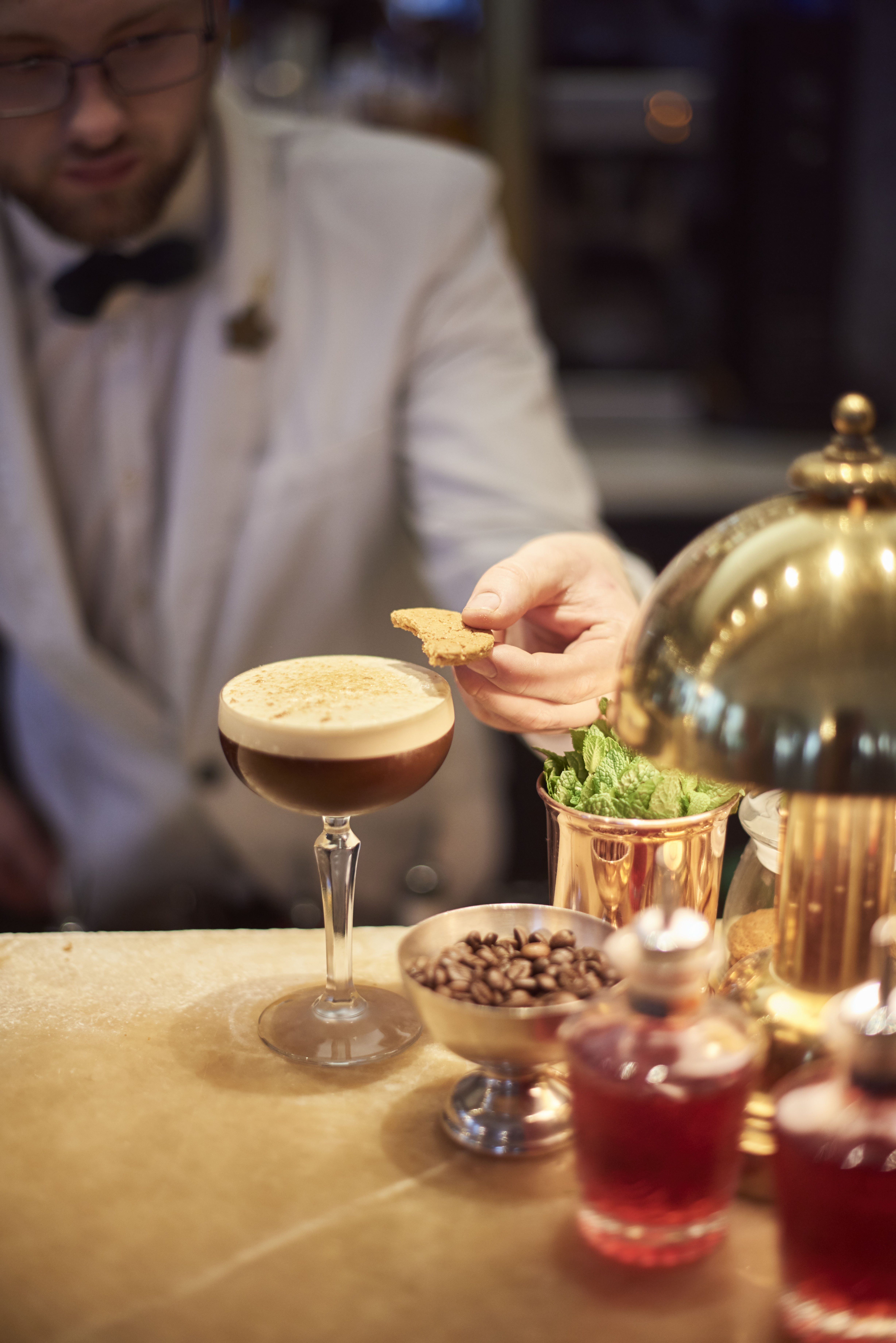 Camarero colocando galletas de mantequilla en un cóctel espresso martini.
