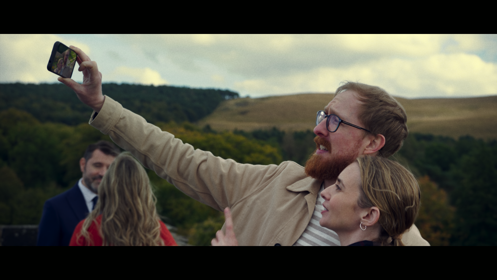 A man takes a selfie with a woman in the grounds of a heritage house