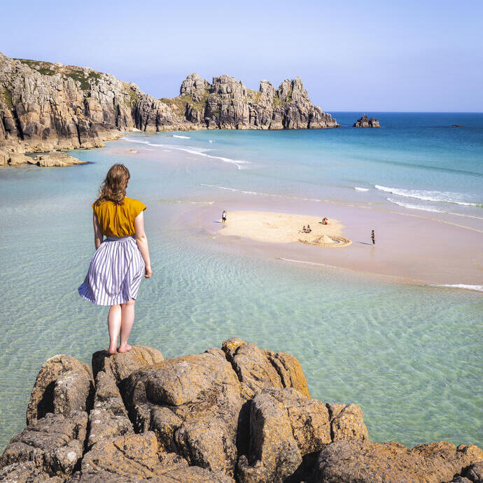 Donna in piedi su una roccia che guarda il mare