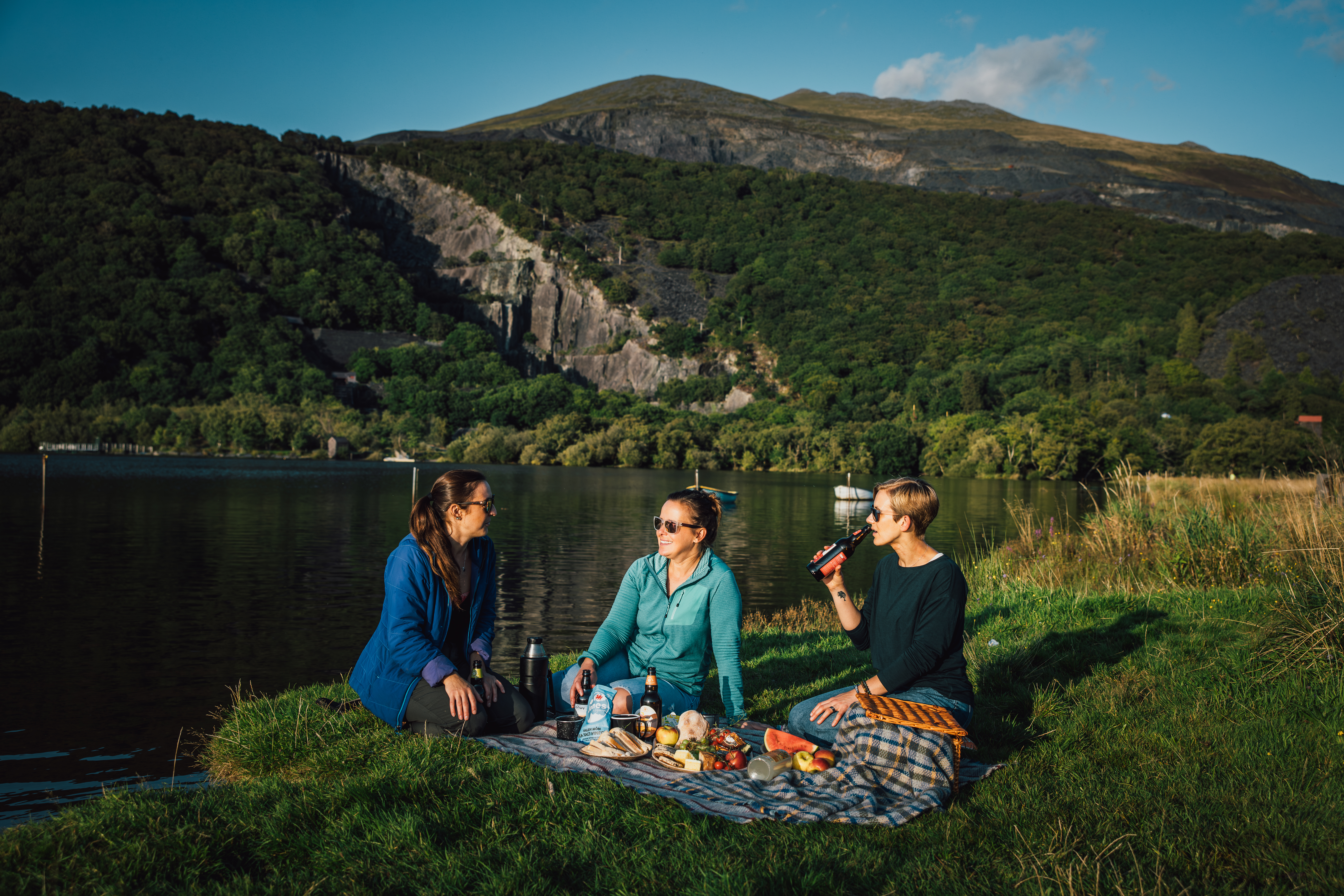 Freunde beim Picknick auf einer Wiese an einem Gletschersee.