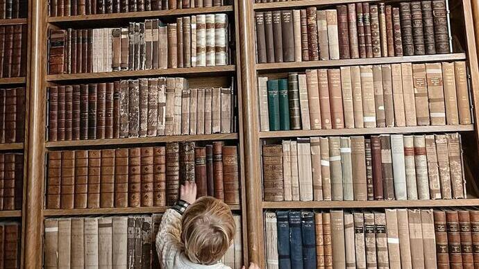 A young visitor looks up at a large book case