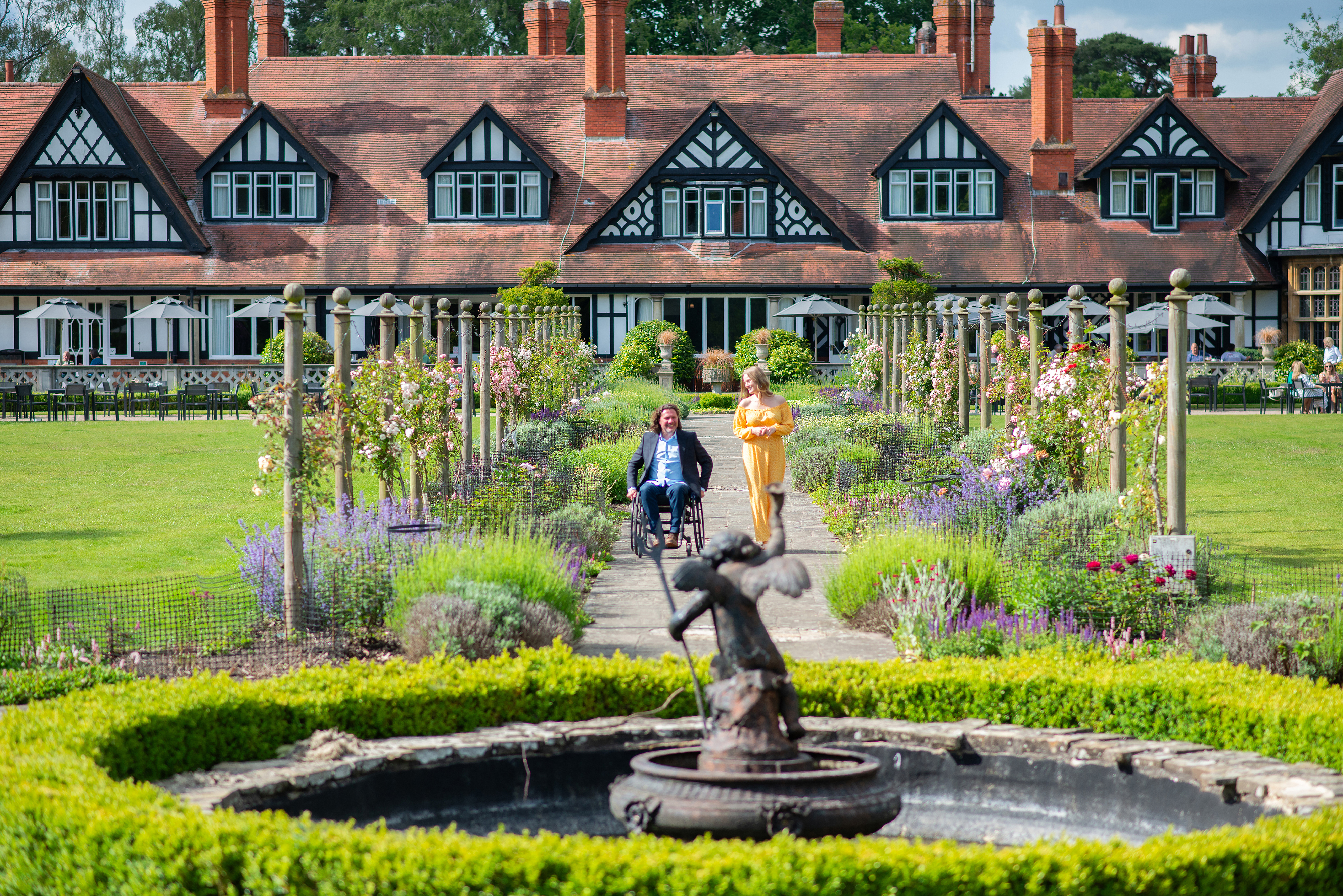 A woman and a man in a wheelchair smiling together in summer gardens