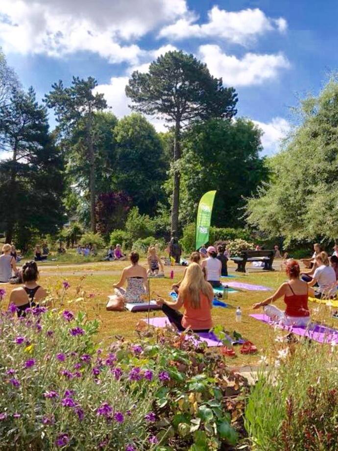 Groups of people taking a yoga session in a park on the Jurassic Coast