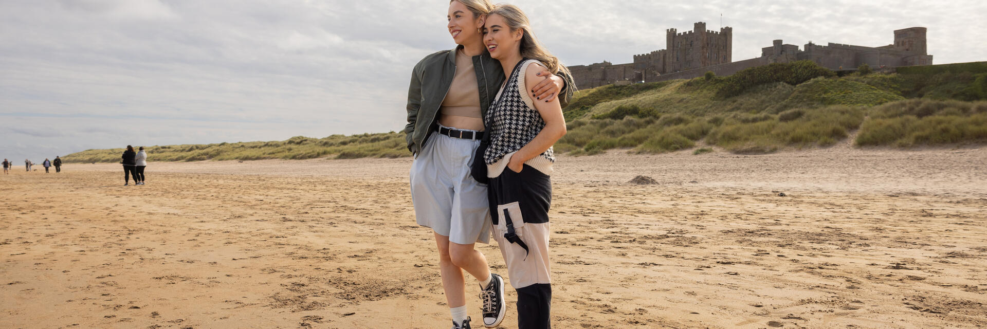 Zwei Frauen umarmen sich am Strand in der Nähe einer Burg