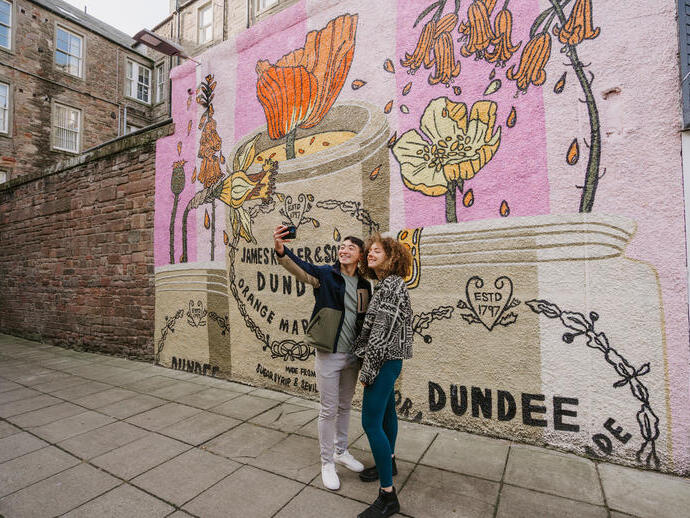 A man and a woman taking a selfie in front of the marmalade mural.