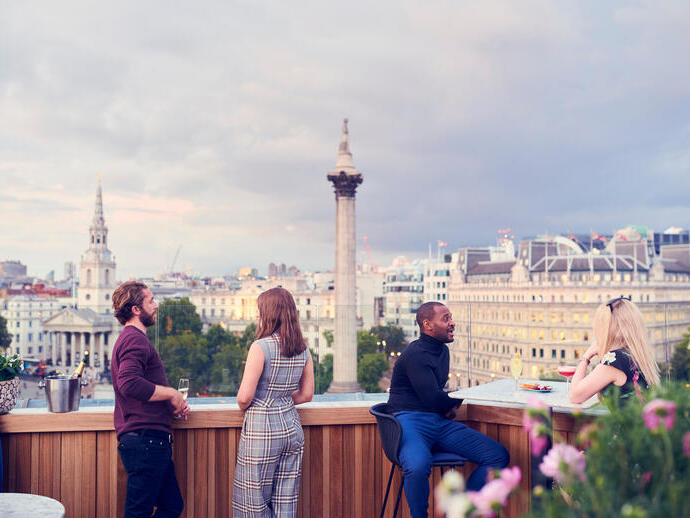 People having a drink at a rooftop bar in a city