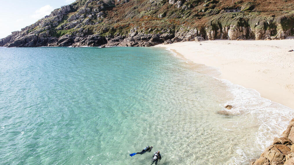 People scuba diving in sea off the coast. Calm seas