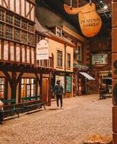 A man standing in an old street, under shop signs