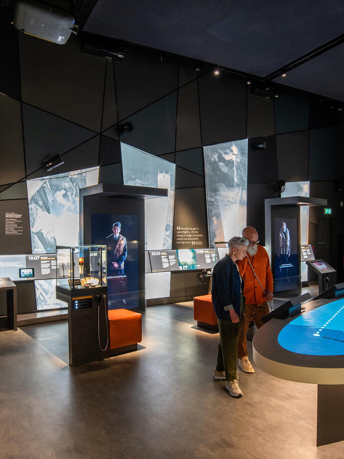 A man and a woman listening to an interactive exhibiton 