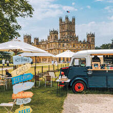 A food truck, parasols and direction signs in the ground of a castle
