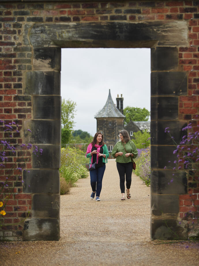 Two women walking toward archway, RHS Bridgewater