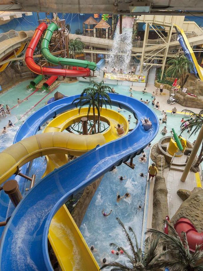 Des personnes s'amusant sur les toboggans d'un parc aquatique couvert.