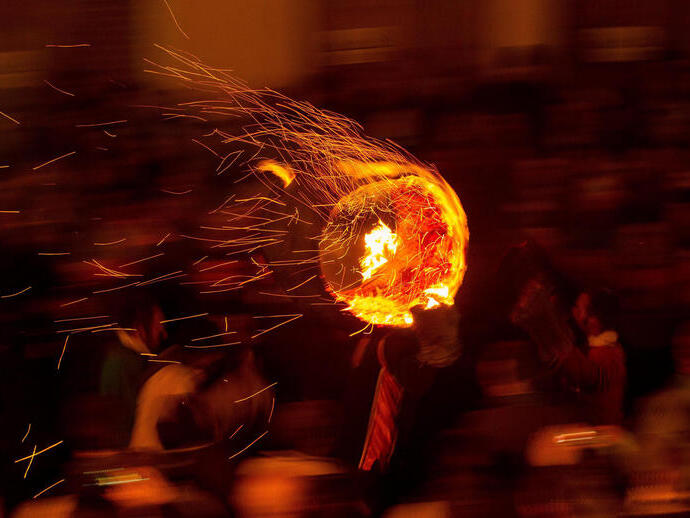Participants run with a burning tar barrel through the streets.