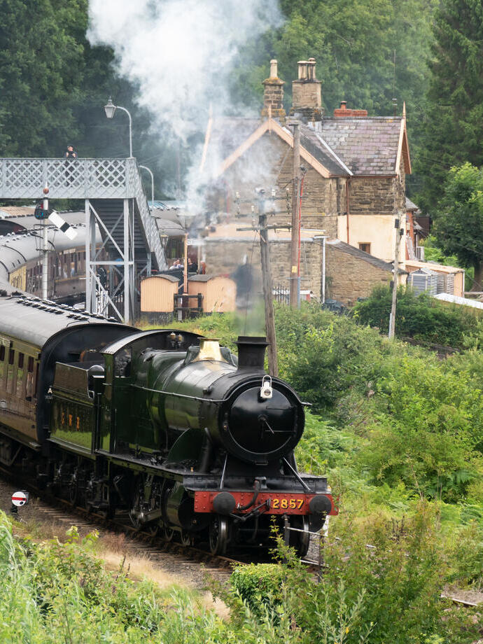 Locomotive 2857 pulling a series of carriages leaving the heritage station