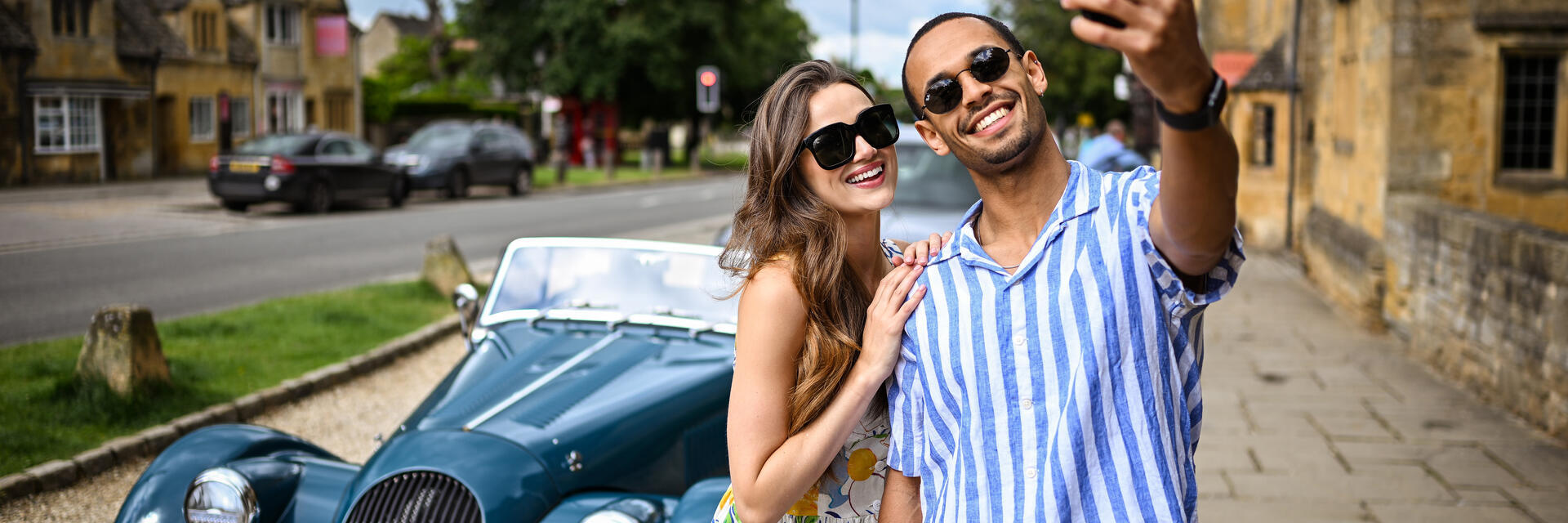 Un hombre y una mujer se hacen un selfi delante de un coche clásico