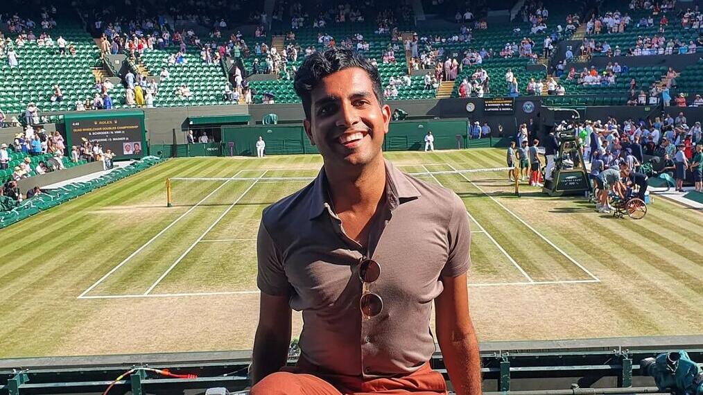 Un uomo seduto su una panchina in uno dei campi del torneo di tennis di Wimbledon