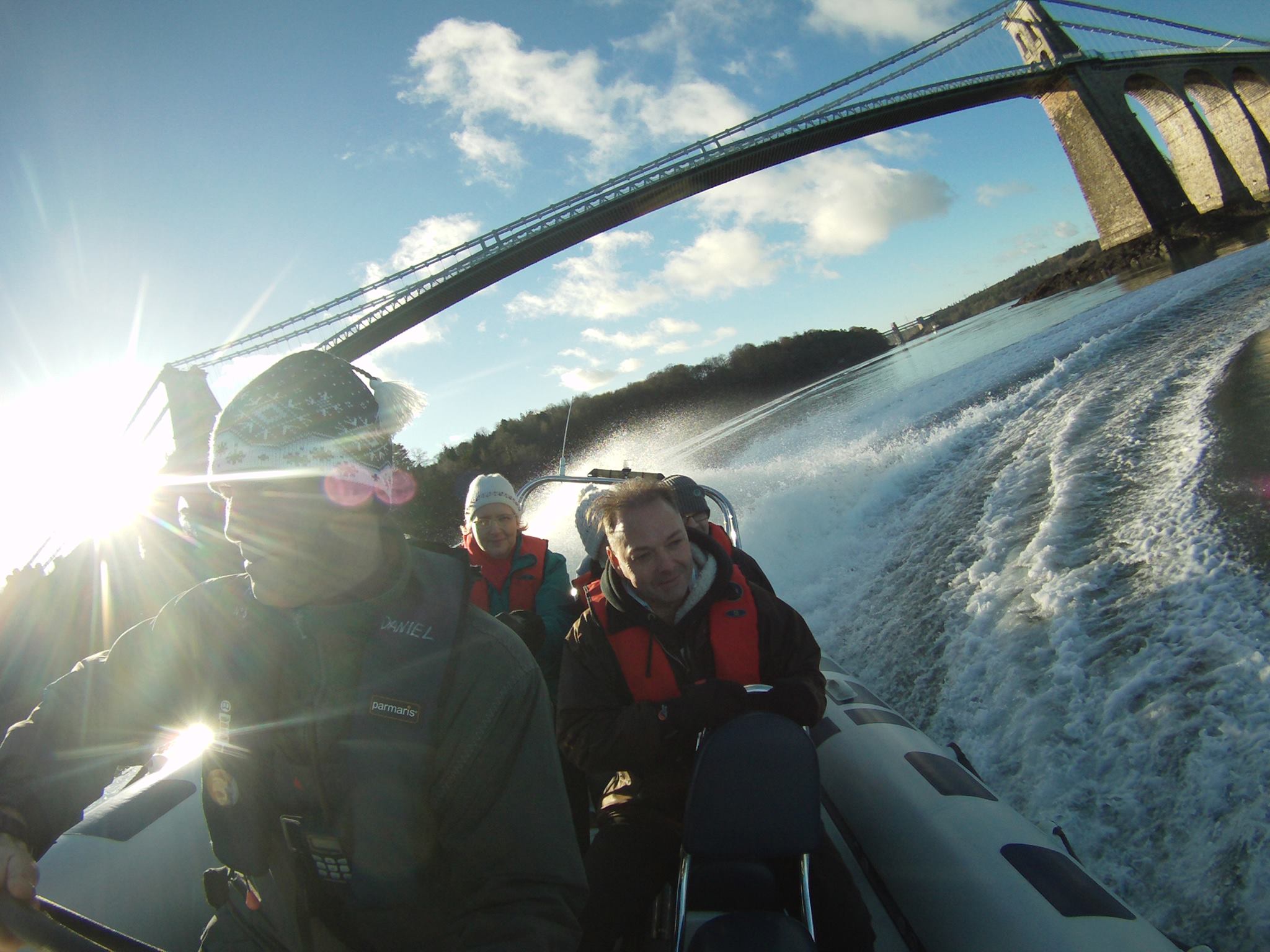 A group of people passing under an iron bridge on a speedboat in Snowdonia/Eryri National Park