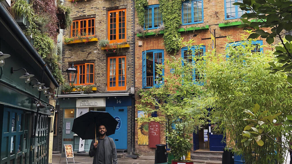 Man with an umbrella walking through a city courtyard