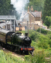 La locomotive 2857 tirant une série de wagons quittant la gare historique.