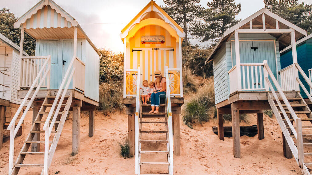 Woman and children sit on the top step of a beach hut