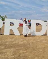Woman in white dress standing in front of UK Black Pride sign