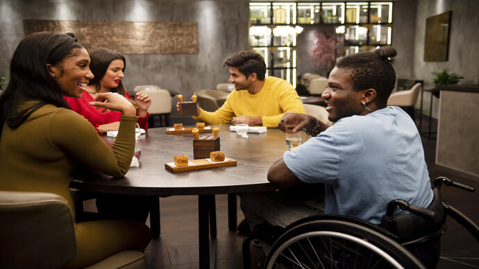 Group of friends, one in a wheelchair sitting at a table in a restaurant