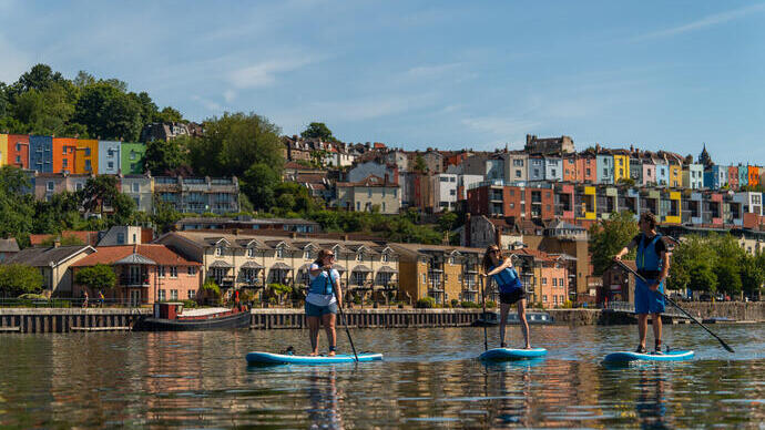Persone che fanno paddleboarding sul fiume con la città di Bristol sullo sfondo