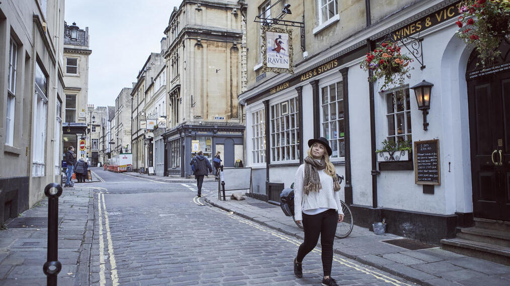 Femme marchant sur une route devant un pub
