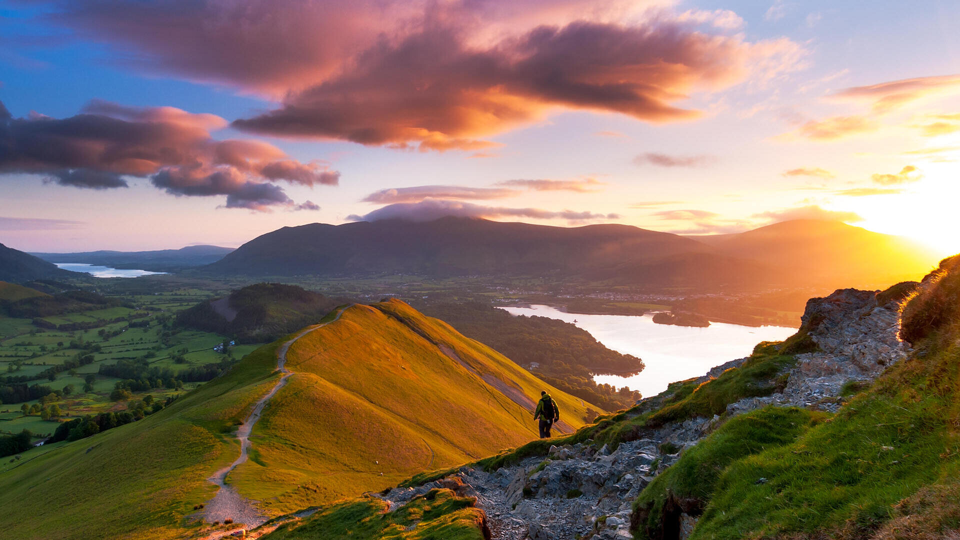 Hiker walking along a path on a mountain ridge at sunrise